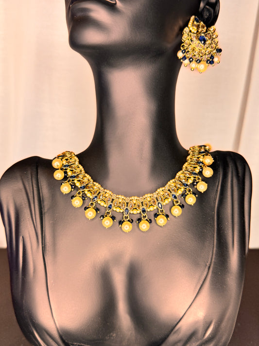 Gold necklace and earrings on a mannequin against a neutral background