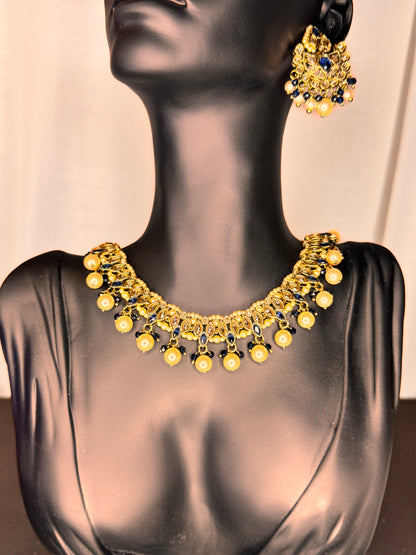 Gold necklace and earrings on a mannequin against a neutral background